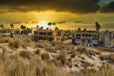 Houses on field against sky during sunset