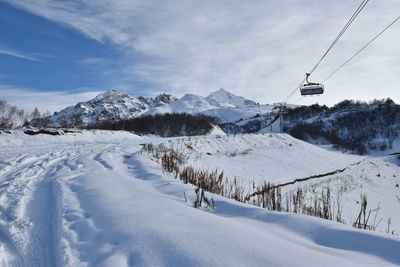 Ski lift over snow covered mountains against sky