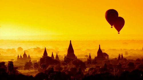 Silhouette of hot air balloons against sky during sunset