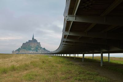 Building on field against cloudy sky