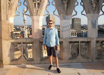 Full length portrait of young man standing against building