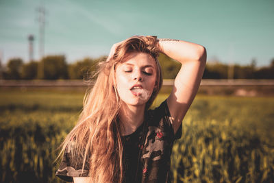Young woman smoking on field
