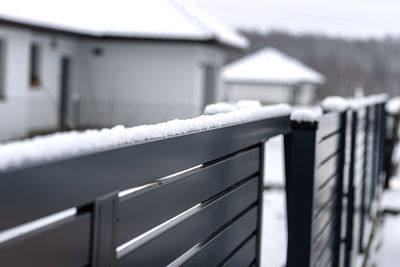 Modern anthracite panel fence with falling snow, visible sliding gate.