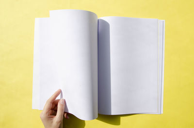 Cropped hands of woman holding blank paper against green background