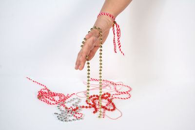 Cropped hand of woman holding christmas decoration against white background