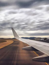 Airplane wing on runway against sky