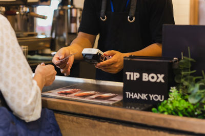 Asia woman use cashless wifi paywave scan on card reader in coffee shop