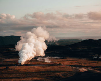 Smoke emitting from volcanic landscape against sky