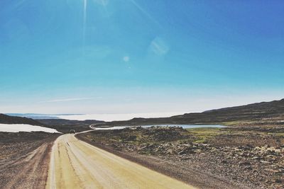 Road passing through landscape against blue sky