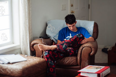 Teenage boy sitting on sofa at home