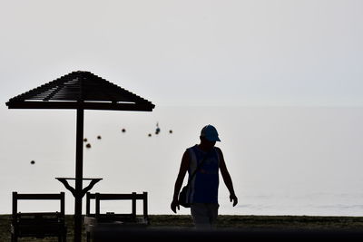 Rear view of man standing on field against clear sky