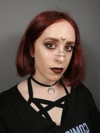 Close-up portrait of a beautiful young woman against wall