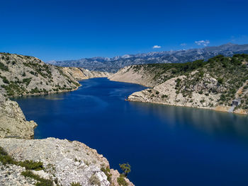 Scenic view of lake and mountains against blue sky