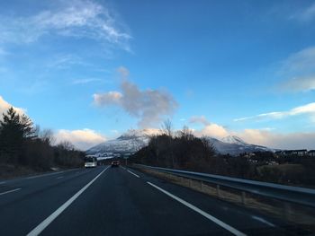 Road by mountains against sky