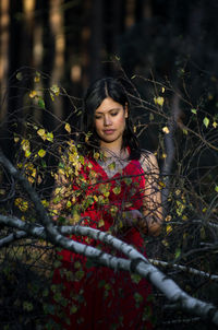 Mid adult woman standing by branches in forest