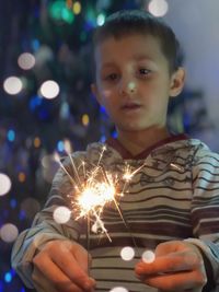 Close-up of boy holding sparkler at night
