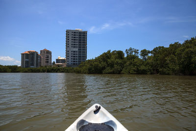 Scenic view of river by buildings against sky