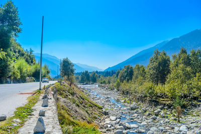 Road amidst trees against blue sky