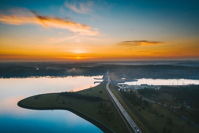 Scenic view of landscape and dam against sky during sunset