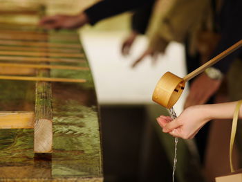 Cropped image of woman washing hands with bamboo ladle