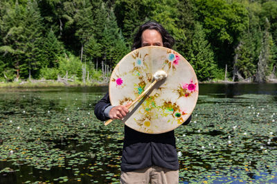 Man holding umbrella while standing by lake