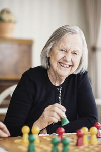 Portrait of happy senior woman playing ludo in nursing home