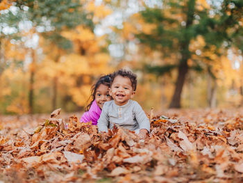 Cute kids sitting on autumn leaves at park