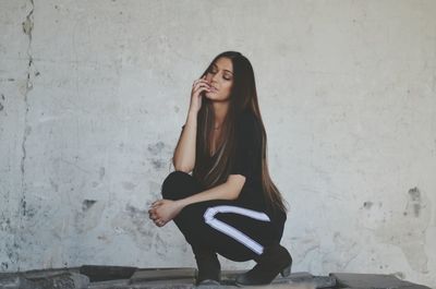 Portrait of young woman standing on wall