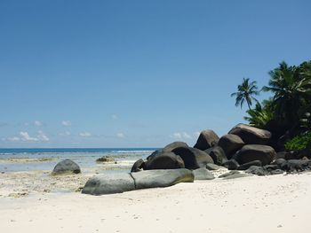 Rocks on beach against clear blue sky