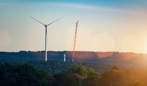 Wind turbines on landscape against sky