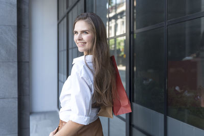 Portrait of smiling woman standing against wall