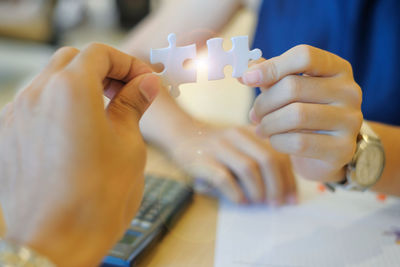 Close-up of business colleagues holding jigsaw pieces