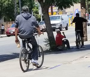 Rear view of man riding bicycle on street