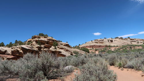 Rock formations on landscape against clear blue sky