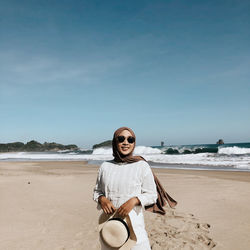 Portrait of woman in hijab standing at beach