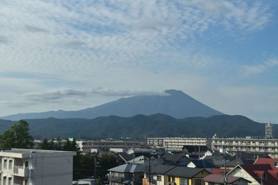 Houses in town by mountains against sky