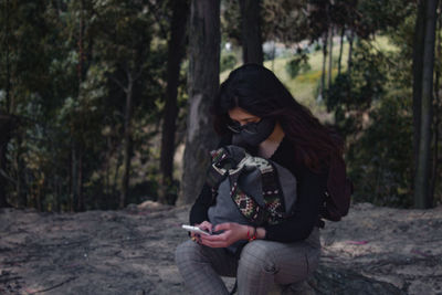 Woman using mobile phone in forest