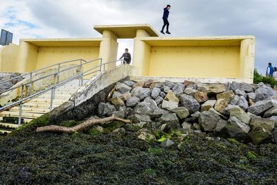 Man standing on rock against sky