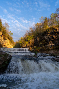 Scenic view of waterfall against sky