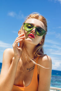 Portrait of young woman wearing sunglasses against sea