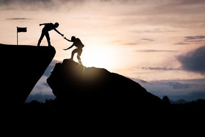 Silhouette people standing on mountain against sky during sunset