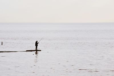 Man standing in sea against clear sky