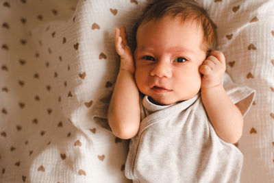 High angle view of cute baby boy lying on bed at home