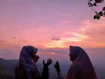 Women on mountain against sky during sunset