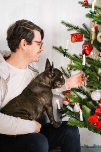 Dog owner and french bulldog by christmas tree