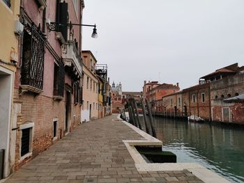 Canal amidst buildings in town against clear sky