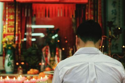 Rear view of man walking on illuminated christmas lights at night