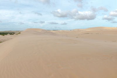 View of sand dunes against cloudy sky