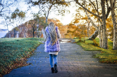 Rear view of woman walking on road during autumn