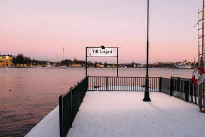 Snow on pier in river against sky